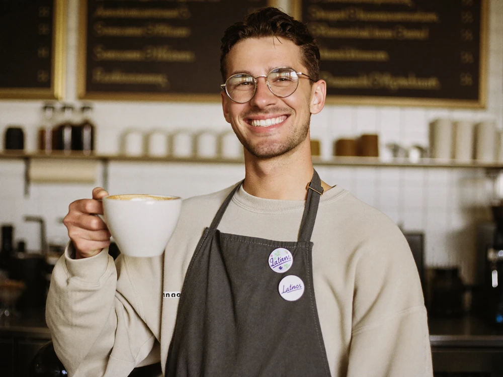 Barista sirviendo un café con leche en una cafetería de barrio